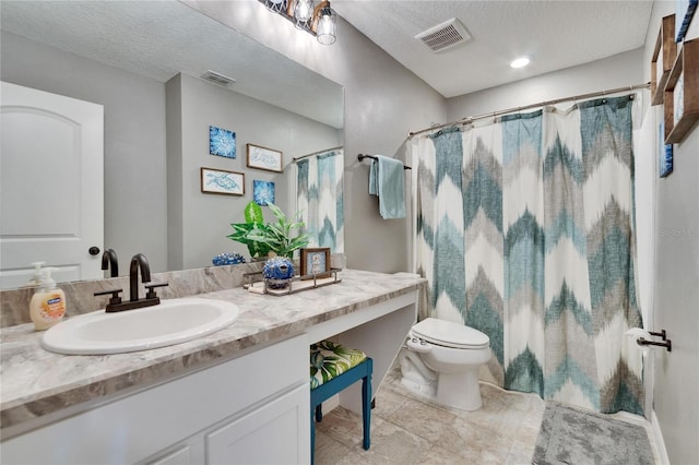 bathroom with visible vents, toilet, vanity, and a textured ceiling