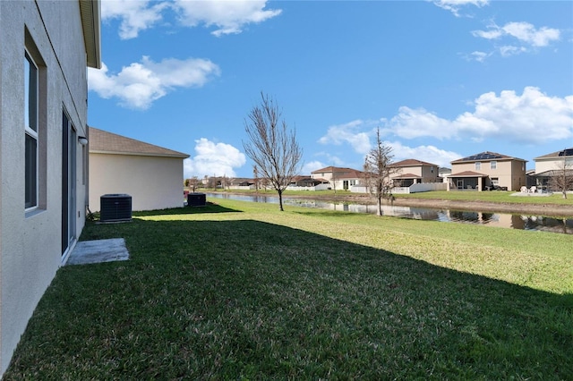 view of yard featuring a residential view, a water view, and central AC