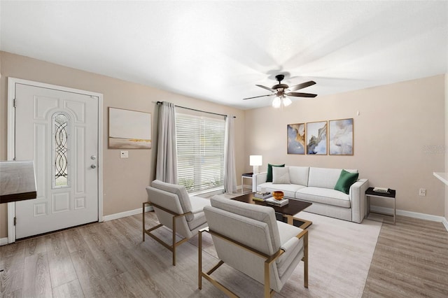 living area with baseboards, ceiling fan, and light wood-style floors