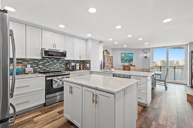 690 Island Way Unit 1003, Clearwater Beach, FL 33767 - kitchen featuring appliances with stainless steel finishes, a peninsula, tasteful backsplash, a sink, and white cabinets