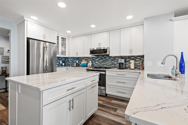690 Island Way Unit 1003, Clearwater Beach, FL 33767 - kitchen featuring appliances with stainless steel finishes, a sink, light stone counters, dark wood-style floors, and backsplash