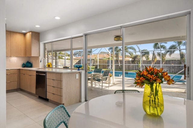 kitchen featuring recessed lighting, dishwashing machine, light countertops, a sink, and light tile patterned flooring