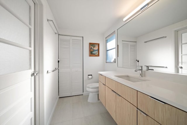 bathroom featuring tile patterned flooring, toilet, vanity, baseboards, and a closet