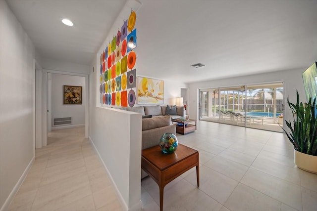 hallway featuring light tile patterned floors, visible vents, and baseboards