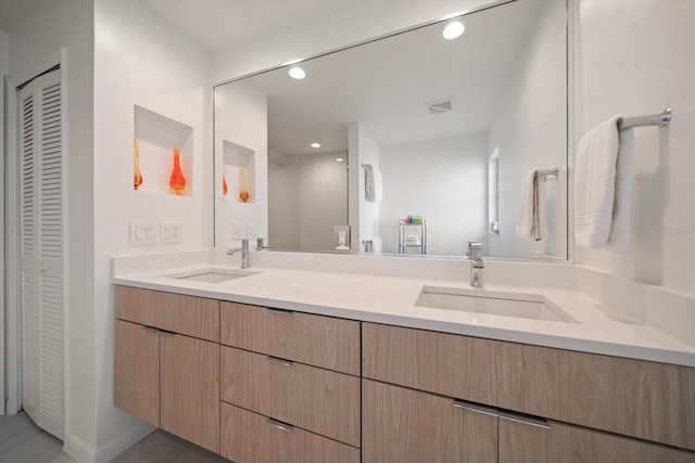 bathroom with recessed lighting, a closet, a sink, and double vanity