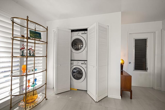 laundry room with laundry area, stacked washer / drying machine, and light tile patterned flooring