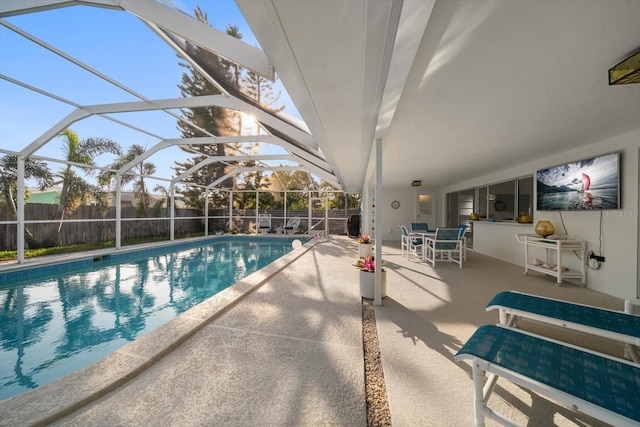 view of swimming pool featuring a fenced in pool, glass enclosure, fence, a bar, and a patio area