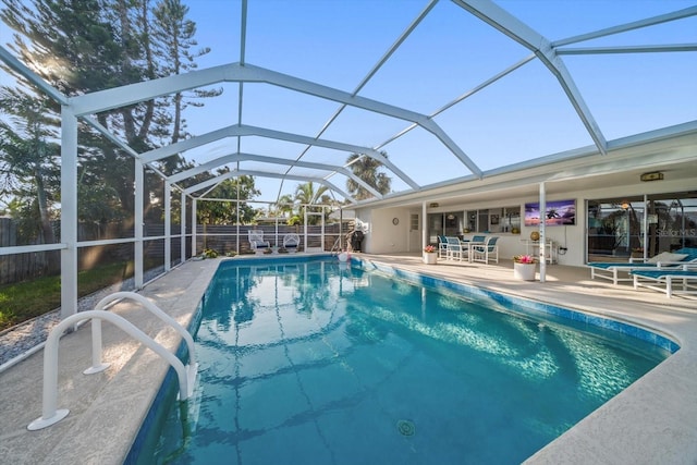 view of pool with glass enclosure, a patio area, a fenced backyard, and a fenced in pool