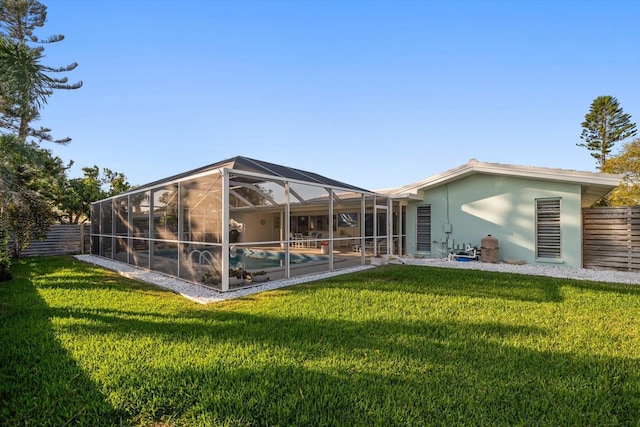 rear view of property featuring glass enclosure, fence, an outdoor pool, and a lawn