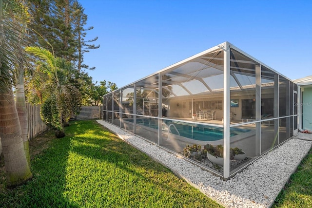 outdoor pool with a lawn, a patio area, a lanai, and a fenced backyard