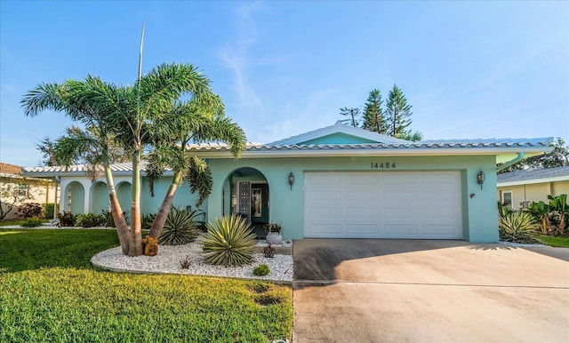 view of front of house featuring stucco siding, concrete driveway, an attached garage, a tiled roof, and a front lawn