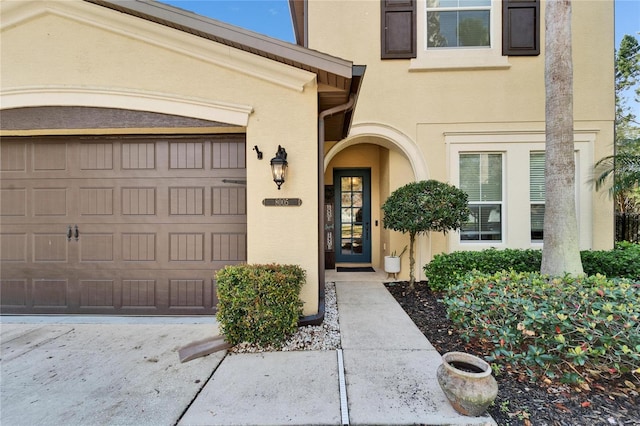 entrance to property featuring an attached garage and stucco siding