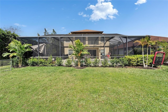 rear view of property featuring a lanai, a yard, and fence