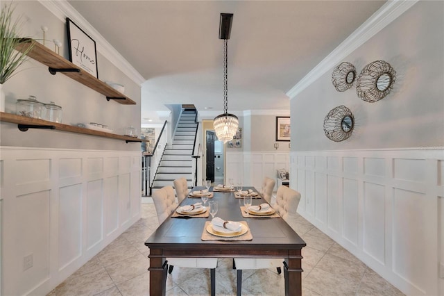 dining area with light tile patterned floors, a decorative wall, stairway, wainscoting, and crown molding