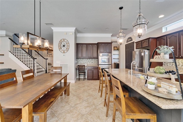 kitchen featuring hanging light fixtures, dark brown cabinetry, visible vents, and appliances with stainless steel finishes