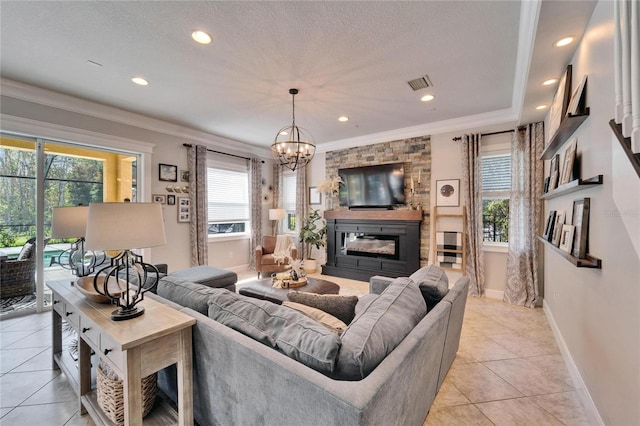 living room with ornamental molding, a glass covered fireplace, visible vents, and plenty of natural light