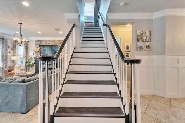 stairway with crown molding, a decorative wall, wainscoting, a textured ceiling, and tile patterned floors