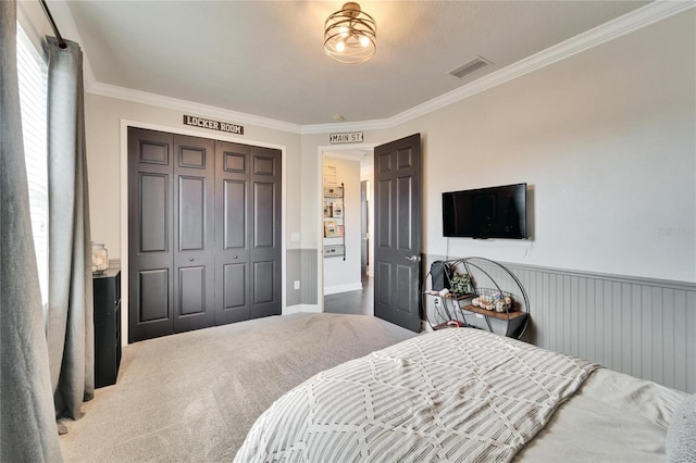 carpeted bedroom featuring a wainscoted wall, ornamental molding, a closet, and visible vents