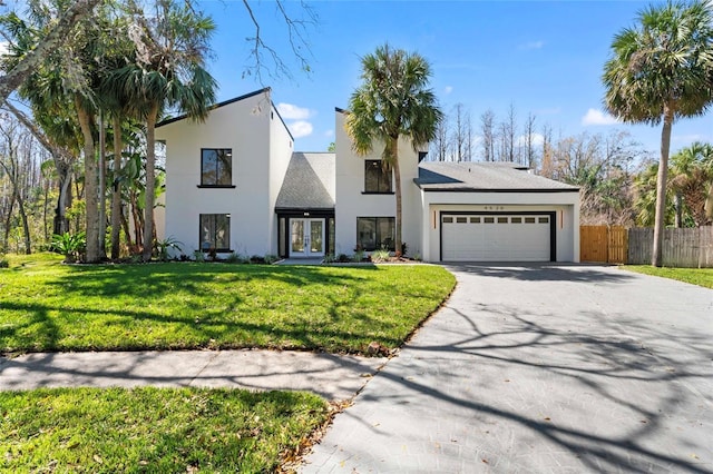 view of front of house featuring a front lawn, french doors, driveway, and an attached garage