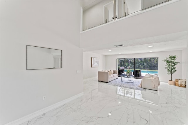 living room featuring marble finish floor, a high ceiling, baseboards, and recessed lighting