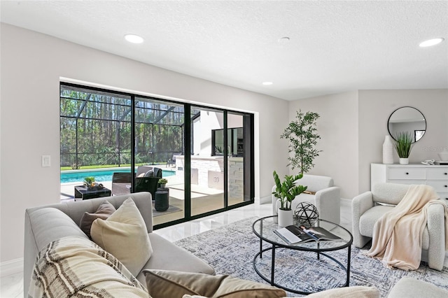 living area featuring a textured ceiling, marble finish floor, baseboards, and recessed lighting