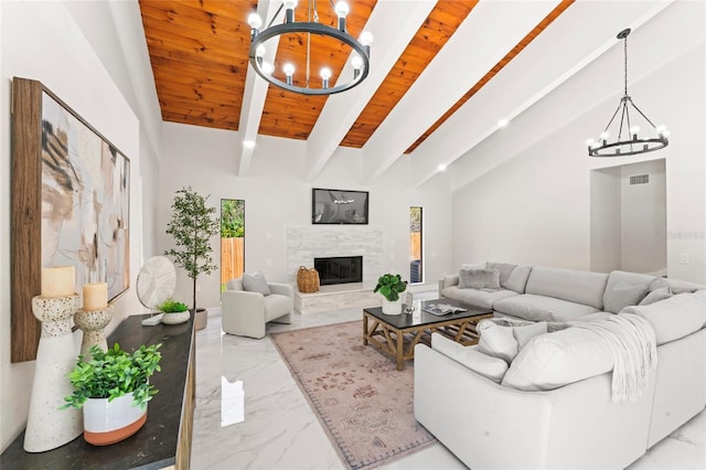 living room with marble finish floor, a notable chandelier, visible vents, a tiled fireplace, and beamed ceiling