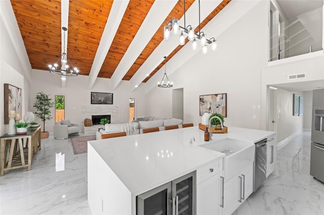 kitchen featuring marble finish floor, stainless steel dishwasher, a fireplace, and a notable chandelier