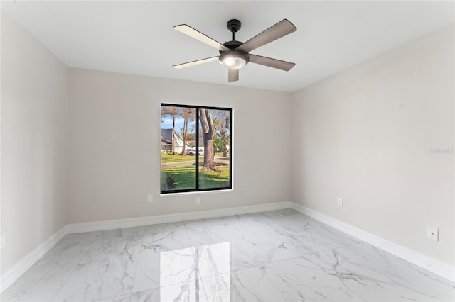 empty room with marble finish floor, baseboards, and a ceiling fan