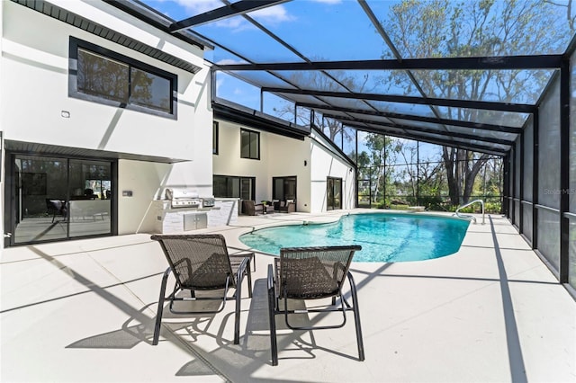 outdoor pool featuring glass enclosure, a patio, grilling area, and an outdoor kitchen