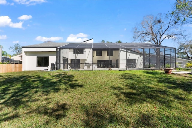 rear view of house featuring a lawn, fence, a lanai, and stucco siding