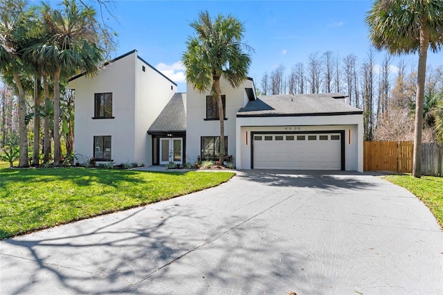 view of front of home with an attached garage, fence, concrete driveway, stucco siding, and a front yard