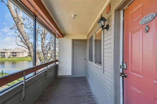 property entrance featuring a water view, a balcony, and stucco siding