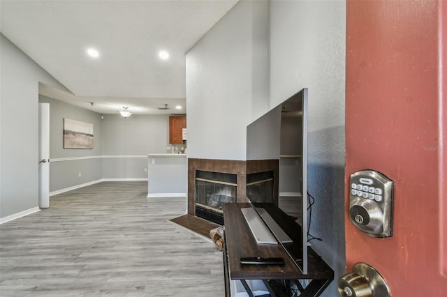 living room with wood finished floors, recessed lighting, a tile fireplace, and baseboards