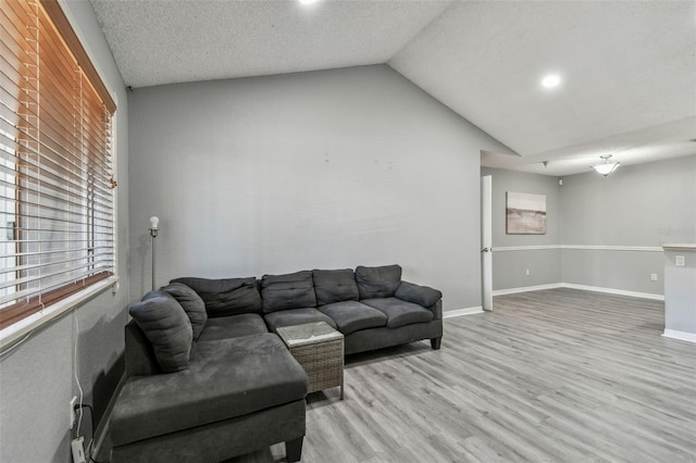 living area with lofted ceiling, light wood finished floors, a textured ceiling, and baseboards