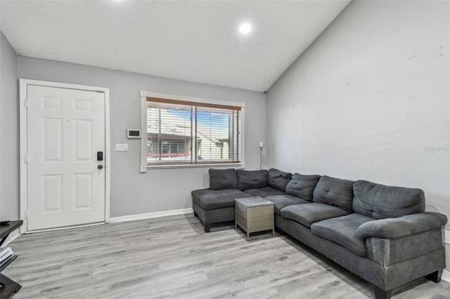 living area with vaulted ceiling, light wood finished floors, and baseboards