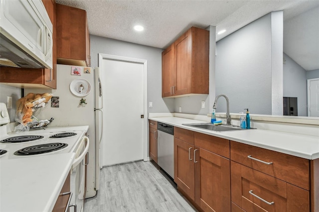 kitchen featuring light countertops, light wood-style flooring, a sink, a textured ceiling, and white appliances