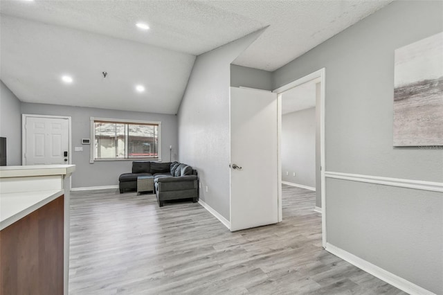 sitting room with light wood finished floors, baseboards, lofted ceiling, a textured ceiling, and recessed lighting