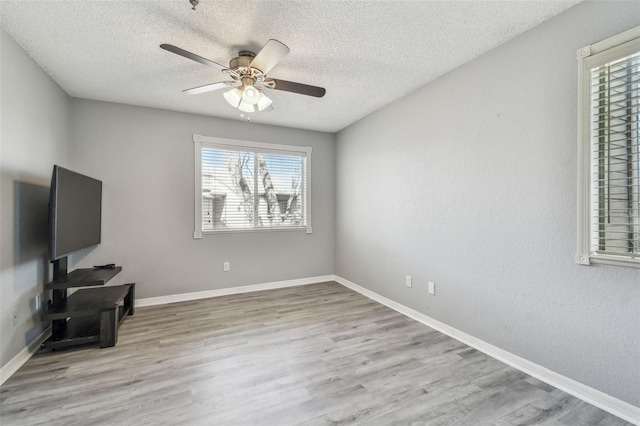 unfurnished living room with baseboards, a textured ceiling, a ceiling fan, and wood finished floors