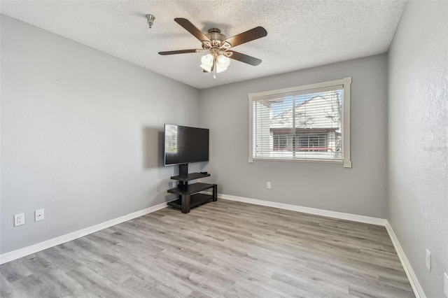 interior space featuring a textured ceiling, baseboards, and wood finished floors