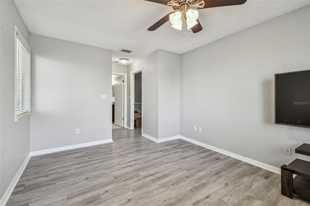 unfurnished living room featuring visible vents, a textured ceiling, baseboards, and wood finished floors