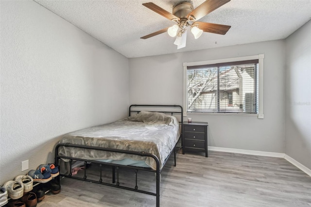 bedroom with a textured ceiling, baseboards, and wood finished floors