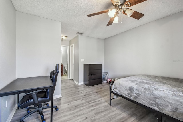 bedroom featuring a textured ceiling, ceiling fan, wood finished floors, visible vents, and baseboards