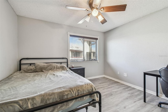 bedroom featuring ceiling fan, a textured ceiling, baseboards, and wood finished floors