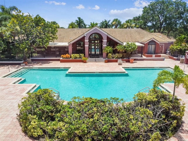 community pool with french doors and a patio