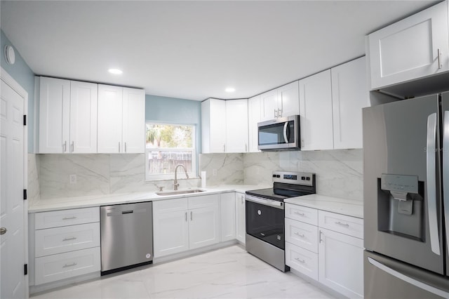 kitchen with appliances with stainless steel finishes, a sink, and white cabinetry