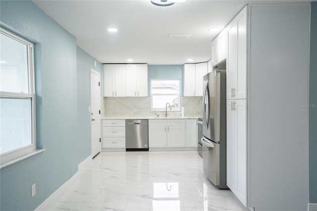 kitchen with stainless steel appliances, white cabinets, light countertops, and marble finish floor