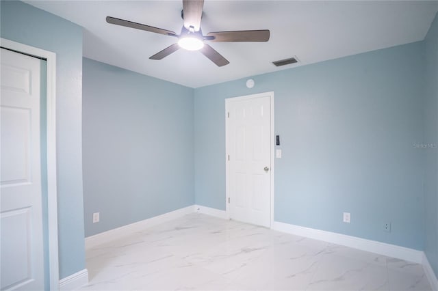 spare room featuring marble finish floor, visible vents, baseboards, and a ceiling fan