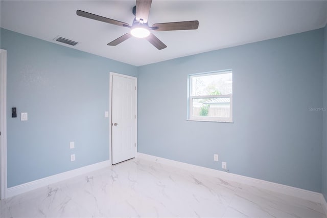 empty room featuring marble finish floor, a ceiling fan, visible vents, and baseboards