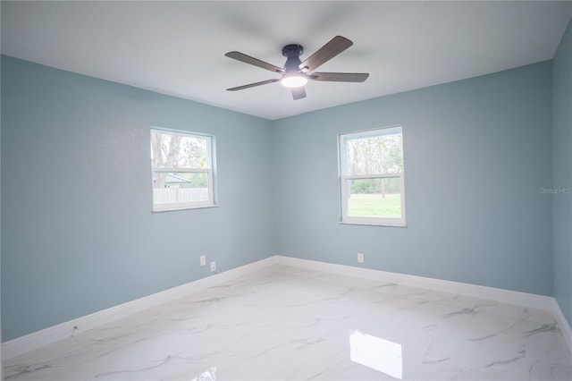 spare room featuring marble finish floor, ceiling fan, and baseboards