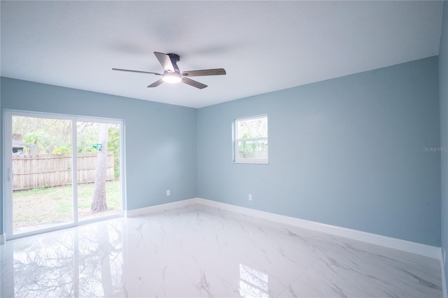 unfurnished room featuring ceiling fan, marble finish floor, and baseboards